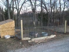 a fenced in area with animals inside of it next to trees and dirt road