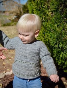 a little boy that is standing in the dirt with his hand out to someone's hand