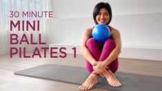 a woman sitting on top of a yoga mat holding a blue ball in her hands