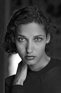 an old black and white photo of a woman with her hand on her chin looking at the camera