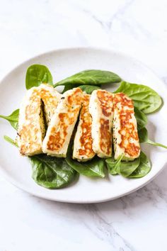 some food is on a white plate with green leafy vegetables and sauce in it