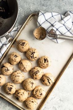 chocolate chip cookies on a baking sheet with a cookie scooper and towel next to it