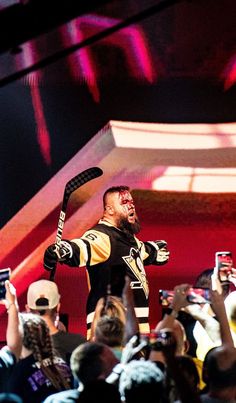 a man in a black and gold uniform is holding up his arms as people take pictures