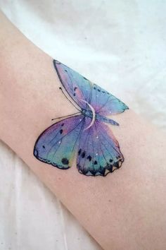 a blue and purple butterfly tattoo on the arm