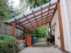 an outdoor area with a pergolated roof and trash cans on the side walk