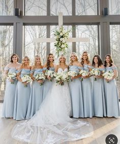 a group of bridesmaids standing in front of a cross