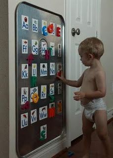 a little boy that is standing in front of a board with magnets on it