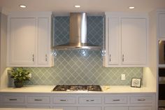 a stove top oven sitting inside of a kitchen next to white cabinets and counter tops