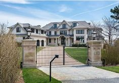 a large white house with a gate in the front yard and driveway leading to it