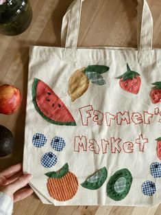 a person holding a tote bag that says farmer's market with fruits and vegetables on it