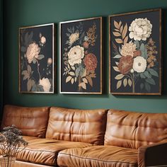 three framed pictures hang on the wall above a leather couch in a green living room