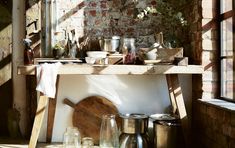 an old kitchen with lots of pots and pans on the stove top in front of a brick wall