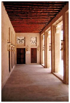 an empty hallway with wooden doors and decorative decorations on the walls, along with tile flooring