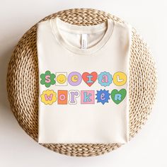 a white t - shirt with the words social worker printed on it sitting next to a wicker basket