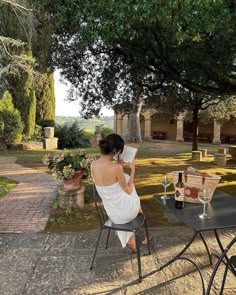 a woman sitting at a table reading a book