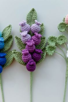 three crocheted flowers with leaves on them