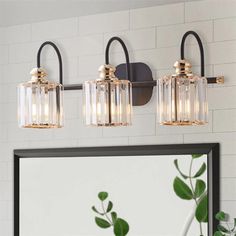 three light bathroom fixture with clear glass and gold accents on the wall next to a mirror