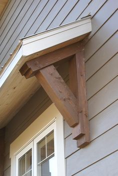 the corner of a house with an open window and wooden brackets on the side of it