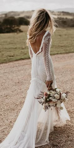 the back of a woman's wedding dress with long sleeves and flowers on it