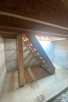 an unfinished attic with stairs leading up to the loft and skylight in the corner