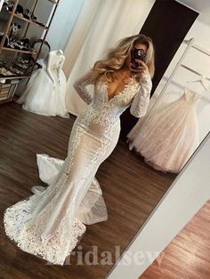 a woman taking a selfie in front of a mirror wearing a white wedding dress