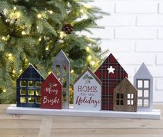 wooden houses are sitting in front of a christmas tree with the words home for the holidays written on them