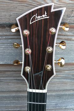 an acoustic guitar headstocked against a wooden background