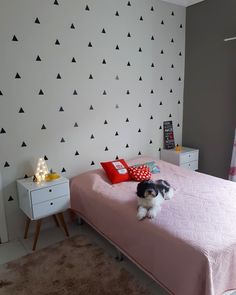 a small black and white dog laying on top of a pink bed in a bedroom