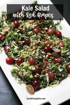 kale salad with red grapes and almonds on a white platter, ready to be eaten