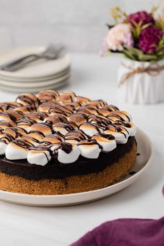 a cake with marshmallows and chocolate on top sitting on a white plate