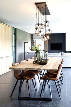 a dining room table with chairs and lights hanging from it's centerpieces