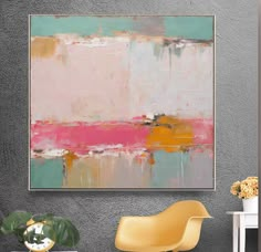 an abstract painting hangs on the wall next to a chair and vase with flowers in it