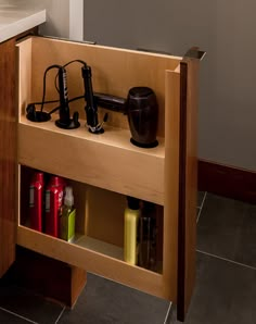 an open cabinet with hair dryers and other items in it on the counter top