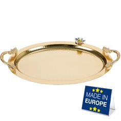 an oval tray with handles made in europe and stars on the rim, is shown next to a blue sticker that says made in europe