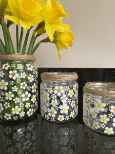 three jars with flowers painted on them are sitting on a counter next to each other