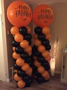 two orange and black balloons with happy halloween written on them in front of a doorway