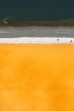 an aerial view of two people riding surfboards in the ocean with yellow water and sand