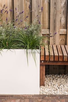 a white planter sitting next to a wooden bench