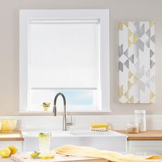 a kitchen with white walls and yellow accessories on the counter top, next to a window