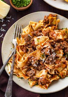 pasta with meat sauce and parmesan cheese on a plate next to a fork