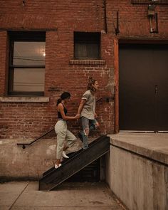 two young women are walking up the stairs to an apartment building and one is holding onto another woman's hand