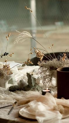 the table is covered with dried plants and other things to decorate for an outdoor event