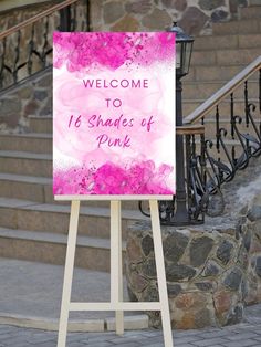 a welcome sign with pink flowers on it in front of some stairs and stone steps