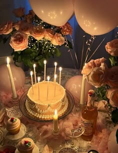 a table topped with a cake covered in frosting and lots of candles next to balloons