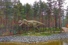 a large dinosaur statue in the middle of a forest