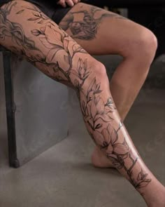 a woman's legs with tattoos on them and flowers all over the leg area