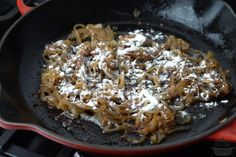 a skillet filled with pasta and sauce on top of an open stovetop burner