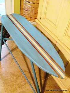 a blue surfboard sitting on top of a wooden table next to a cabinet in a kitchen