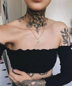 a woman with tattoos on her chest wearing a black off the shoulder cropped top