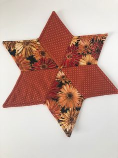 an orange and brown star shaped pillow on a white surface